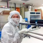 Gowned woman points to wafers in nanofabrication cleanroom
