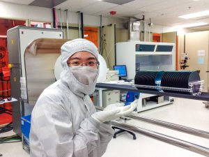 Gowned woman points to wafers in nanofabrication cleanroom