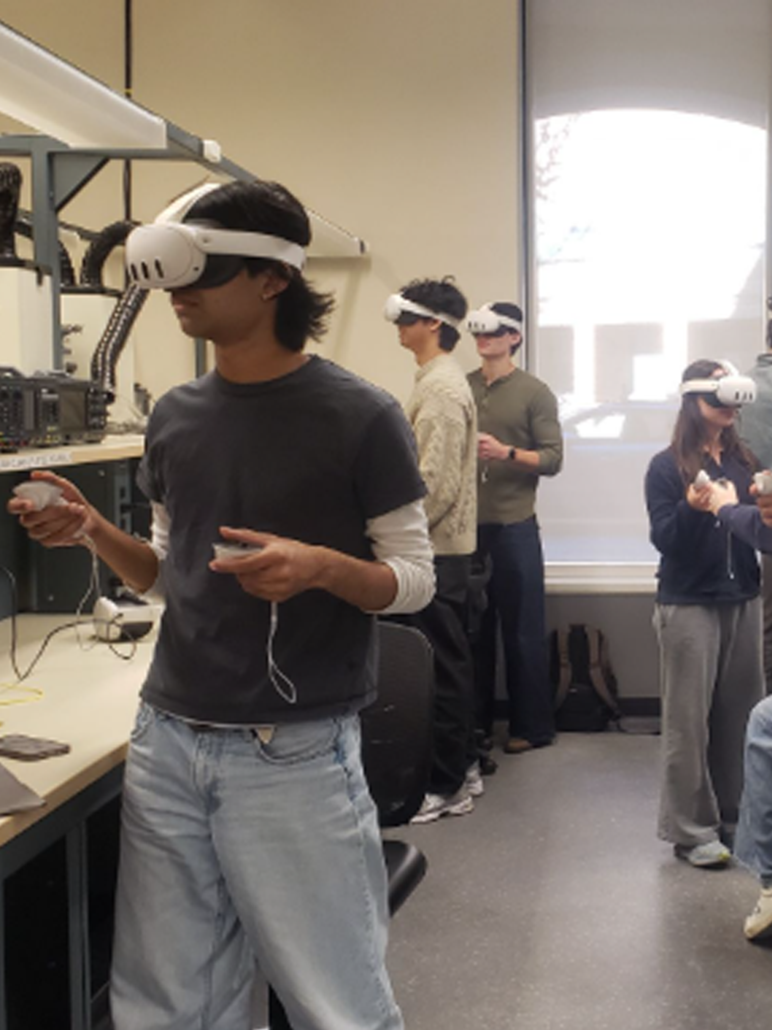 Students standing in lab wearing virtual reality headsets and holding controllers in their hands.